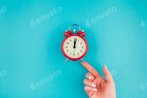 Preview: Woman hand holding the red vintage alarm clock