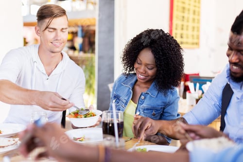 Preview: happy friends eating at restaurant