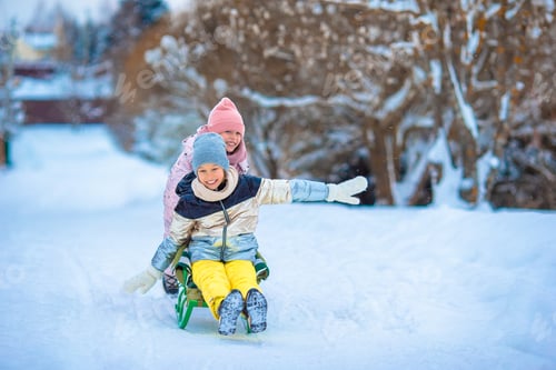 Preview: Adorable little happy girls sledding in winter snowy day