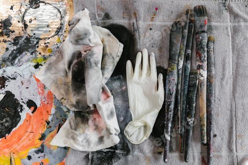 Preview: Artist studio paint items. Brushes and smeared cloth with disposable gloves.