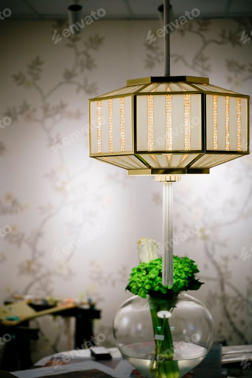 Preview: a white flower vase is near a lamp hanging from a ceiling
