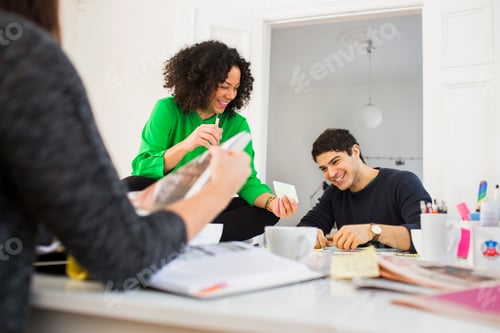 Preview: Happy businesswoman showing adhesive note to male colleague in office