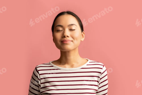 Preview: Portrait Of Calm Asian Woman Standing With Closed Eyes On Pink Background