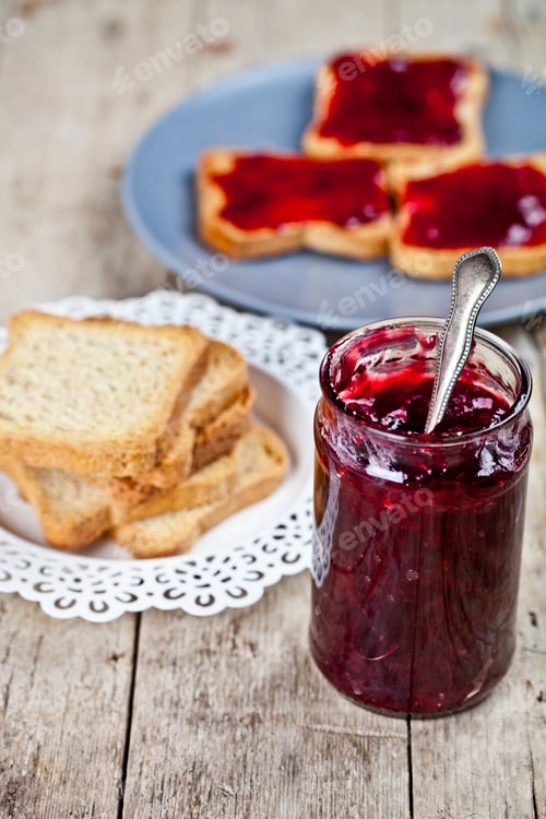 Preview: Homemade cherry jam and fresh toasted cereal bread slices plates closeup.