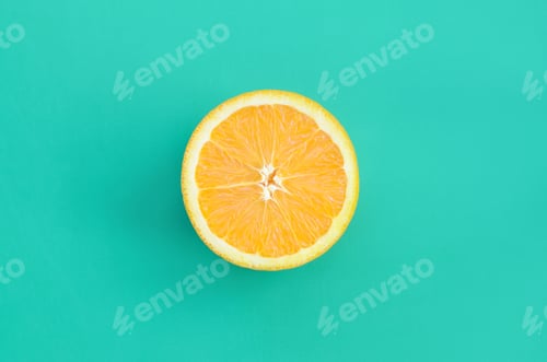 Preview: Top view of a one orange fruit slice on bright background in turquoise green color