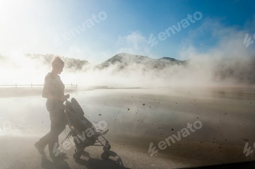 Preview: A woman and a child in a buggy in rising steam from thermal pools