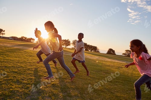 Preview: Four children running barefoot uphill in a park