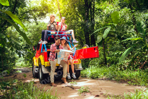 Preview: Happy asian young travellers with 4WD drive car off road in forest.