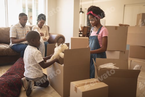 Preview: African American children unpacking their belongings and parents sitting on sofa at home