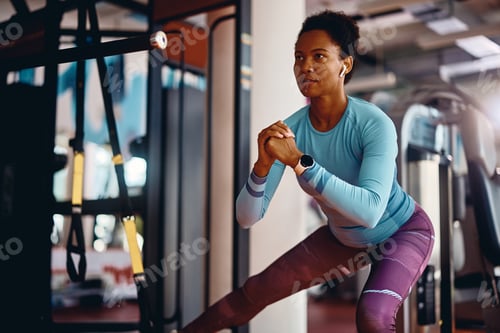 Preview: Black female athlete doing side lunges during sports training in a gym.