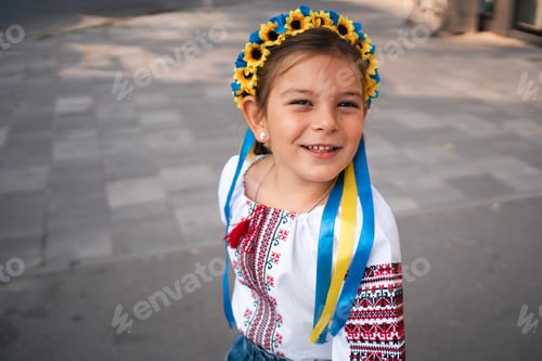 Preview: Child girl in Ukrainian traditional clothes and flower wreath is praying outdoors in a sunlight