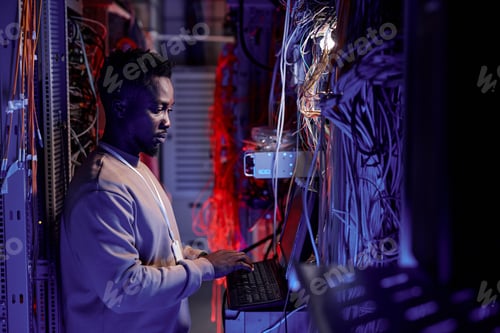 Preview: System administrator using computer in server room neon light