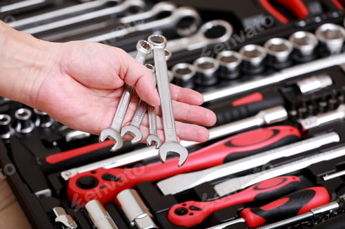 Preview: Tool store. Closeup of male hand holding wrenches. Auto repair kit in toolbox.