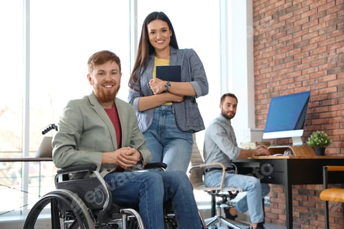 Preview: Young man in wheelchair with colleagues at office