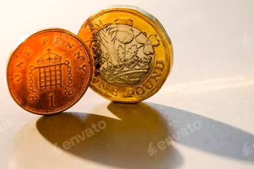 Vista previa: Primer plano de las monedas británicas de una libra y un centavo del Reino Unido contra la luz del sol.