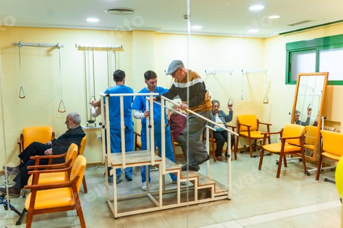 Preview: Elderly man doing rehabilitation exercises climbing stairs with physiotherapists assisting