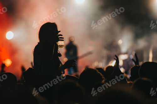 Preview: Silhouette of a woman with raised hands on a concert