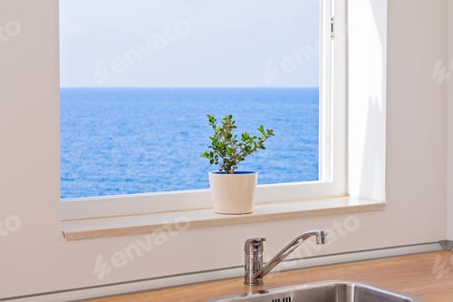 Preview: View of seascape through an open window in kitchen with flower in pot on windowsill