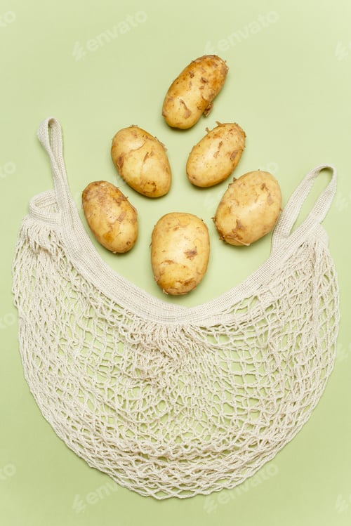 Preview: Trendy string bag with fresh young potatoes inside over light green background