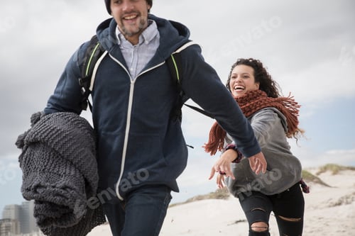 Preview: Happy couple running on a sandy beach