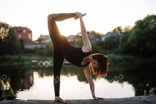Preview: Pretty slim sexy woman doing yoga exercises on the rocks on the river bank