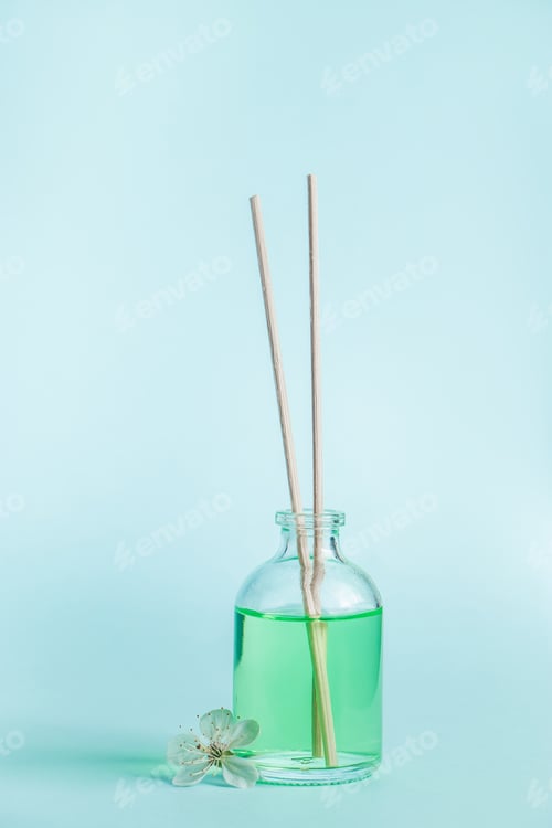 Preview: Aromatic diffuser and flowers on a blue background. Spa and relaxation concept. Fragrances for home.