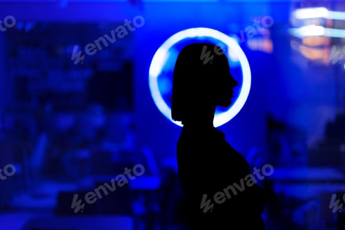 Preview: Woman profile black shape standing in a luminescent circle on a blue illuminated glass background