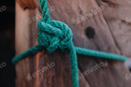 Preview: detail of a knot on a green rope tied around wooden timber