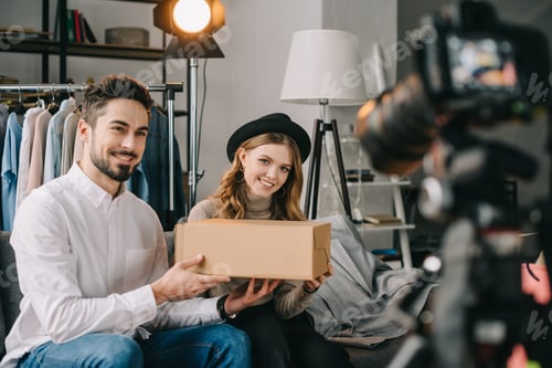 Preview: smiling fashion bloggers holding box