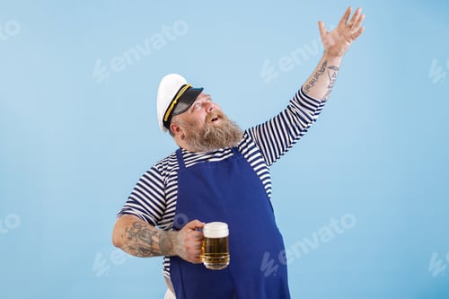 Preview: Positive plump man in sailor costume holds beer raising up hand on blue background