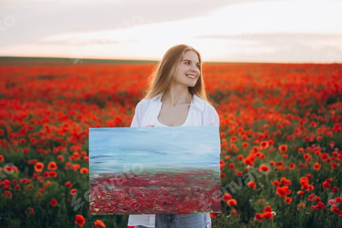 Preview: Young artist holding painting in poppy field at sunset