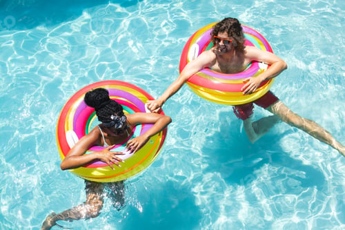 Preview: Diverse couple young African American woman and young Caucasian man relax on colorful pool floats