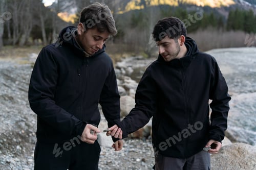Preview: Young men exploring nature holding stones