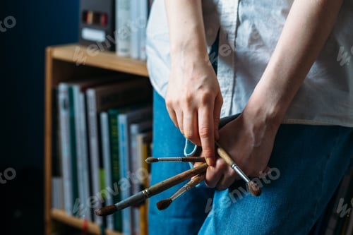 Preview: Female hands hold paint brushes.