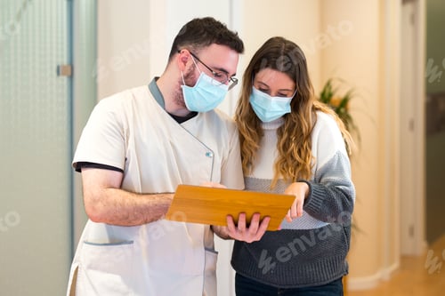 Preview: Female patient in mask consulting with doctor in clinic