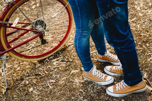 Preview: Couple of lovers with green sneakers and jeans standing next to a vintage bicycle