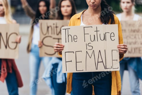 Preview: cropped view of girl holding placard with inscription the future is female near feminists on street