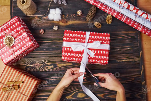 Preview: Girl making gift box. Top view of christmas festive frame with new year decorations