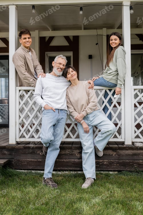 Preview: family photo, parents day, middle aged parents posing next to daughter and young adult son on porch