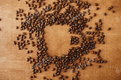 Preview: Coffee cup shape made in roasted coffee beans on wooden table