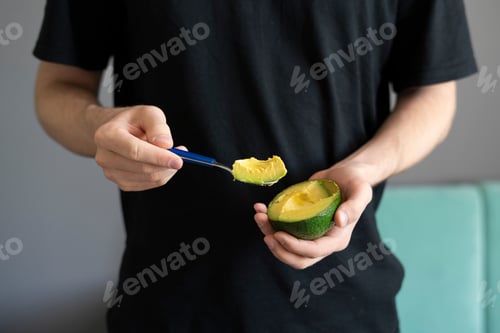 Preview: a person holding half of raw avocado and eating it on breakfast