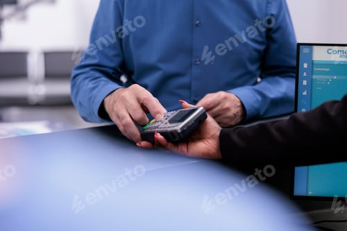 Preview: Senior patient typing credit card pin on pos paying for medication treatment and examination during