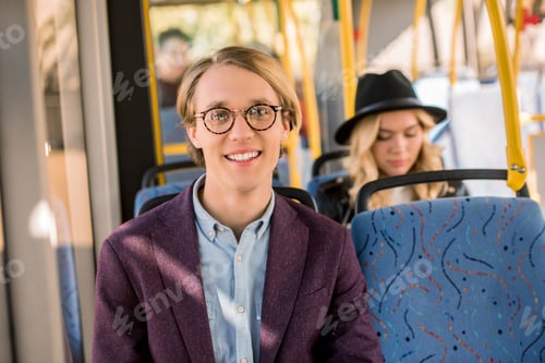 Preview: handsome young man in eyeglasses smiling at camera in bus