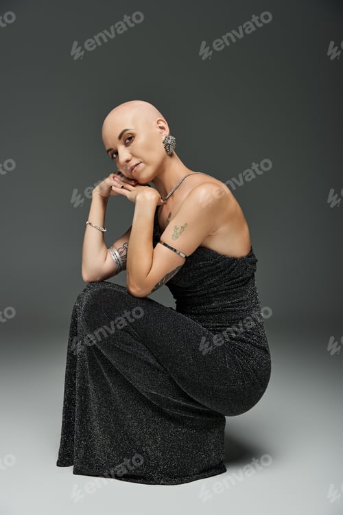 Preview: Elegant portrait of a poised young woman with alopecia wearing a shimmering dress in soft lighting