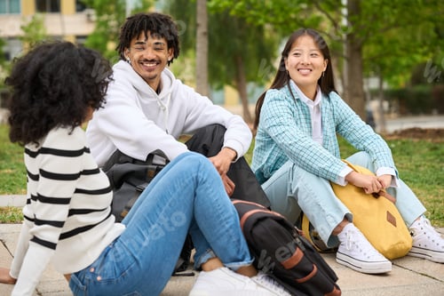 Preview: Three young students are sitting on a bench in a park