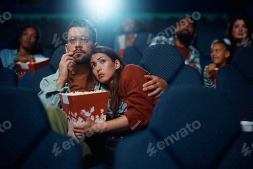Preview: Young woman embracing her boyfriend while watching movie in cinema.