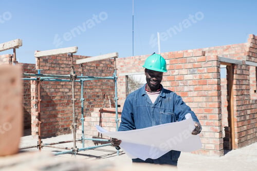 Preview: Builder looking at blueprint on construction site