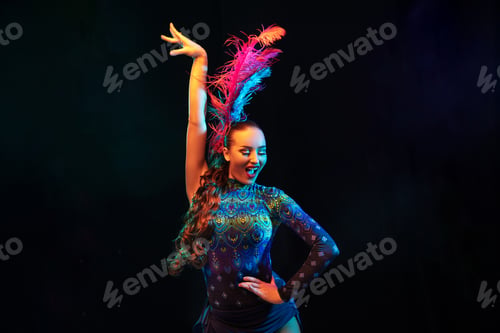 Preview: Beautiful young woman in carnival and masquerade costume in colorful neon lights on black background