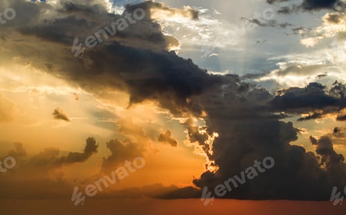 Preview: Bright sunset with setting sun behind vivid orange and yellow clouds