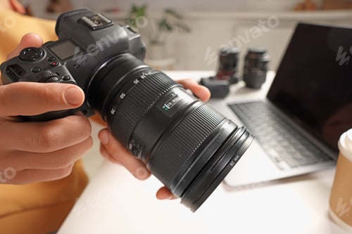 Preview: Photographer with professional camera at white desk indoors, closeup